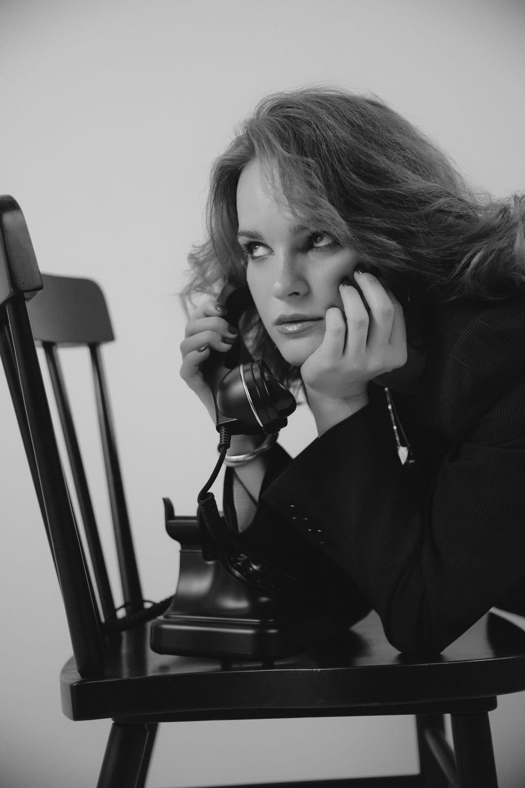 Black-and-white portrait of a woman on a vintage telephone, pensive and cinematic, during her Body & Soul discovery call.