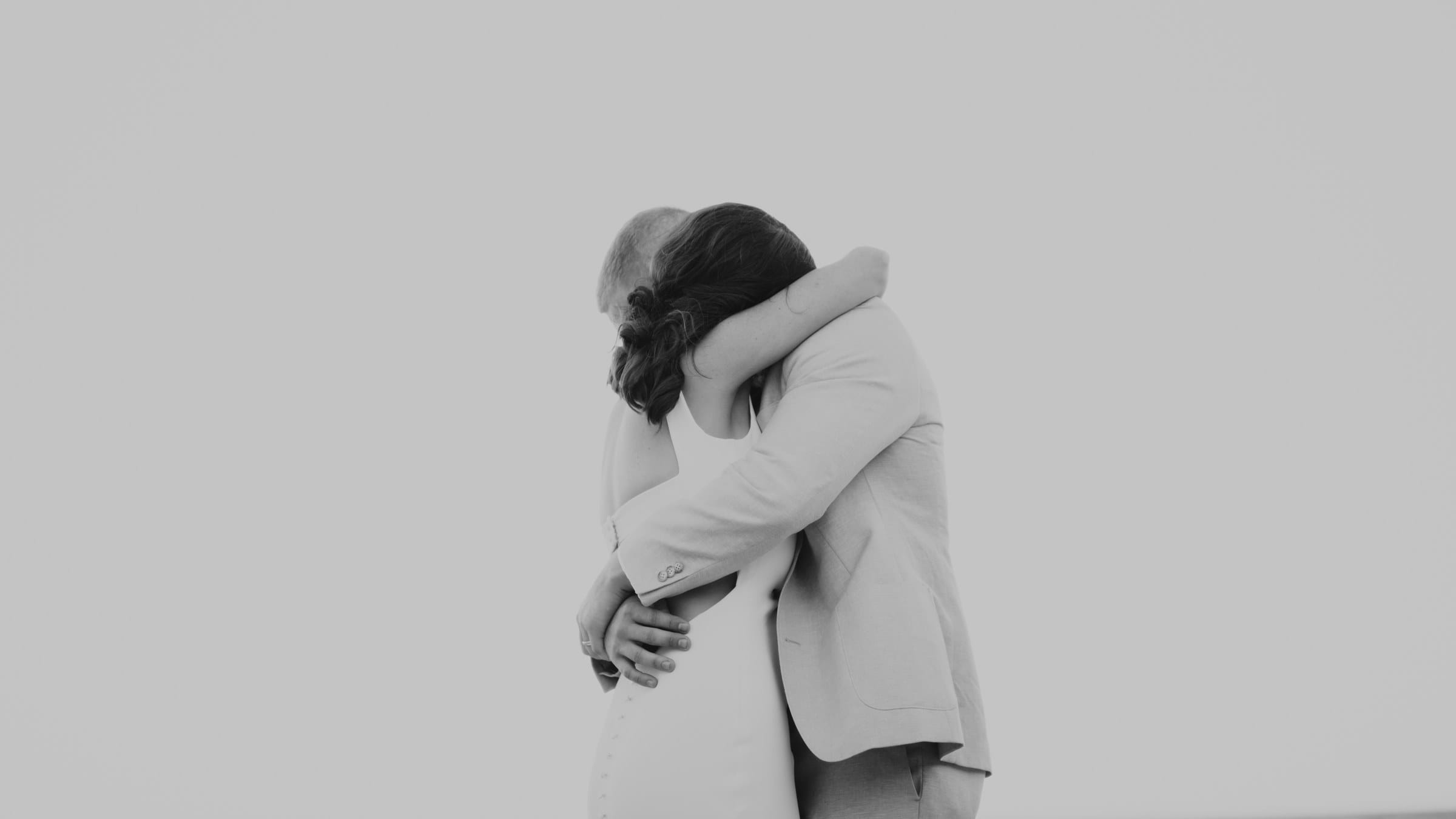 A couple embracing on their wedding day, in black and white.
